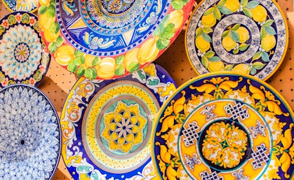 Traditionelle farverige keramik tallerkener fra Amalfi-kysten med håndmalede blå og gule mønstre, populære souvenirs fra Italien