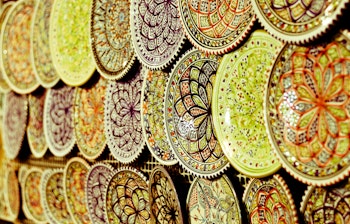 Farverige håndlavede keramiske tallerkener udstillet på et traditionelt marked i Marokko, orientalsk kunsthåndværk
