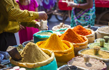 Farverige krydderier og urter udstillet på et traditionelt gademarked i Delhi, der viser Indiens kulinariske rigdom