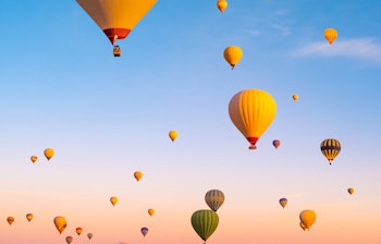 Farverige luftballoner svæver over det unikke landskab i Kappadokien, Tyrkiet ved solopgang