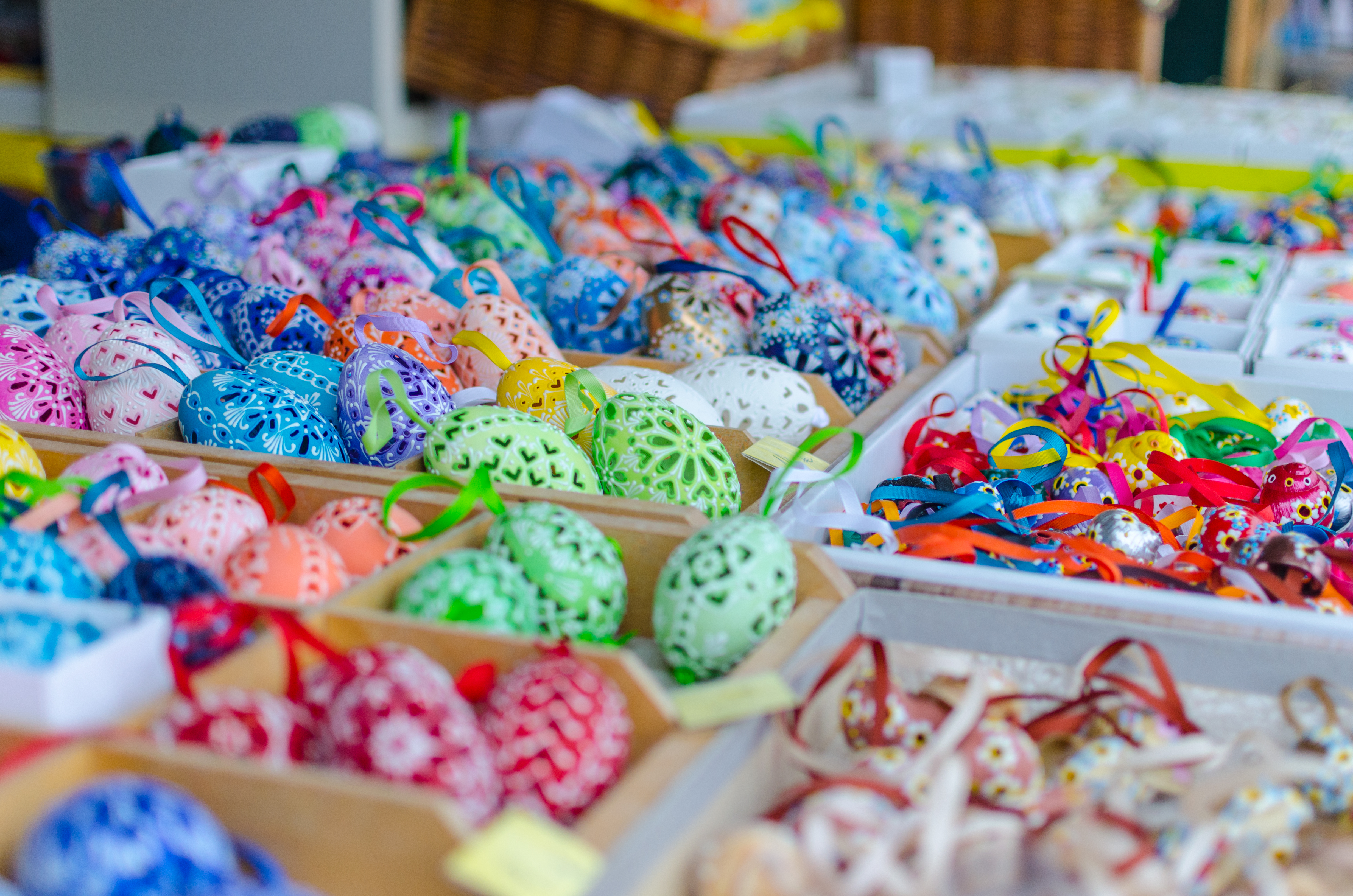 Farverige håndlavede påskeæg med detaljerede mønstre til salg på et traditionelt marked i Wien, Østrig, arrangeret i træbakker med festlige bånd