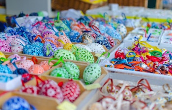 Farverige håndlavede påskeæg med detaljerede mønstre til salg på et traditionelt marked i Wien, Østrig, arrangeret i træbakker med festlige bånd