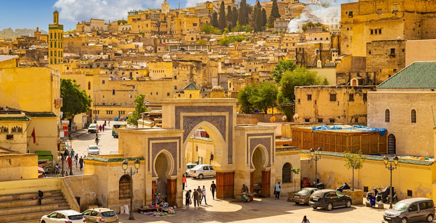 Den historiske medina i Fes, Marokko med den ikoniske byport og gyldne bygninger i den gamle bydel under blå himmel