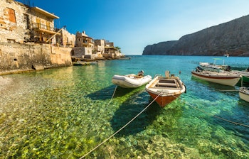 Traditionelle fiskerbåde i det krystalklare turkisblå vand ved Gerolimenas fiskerlejet på Mani-halvøen i Peloponnes, Grækenland