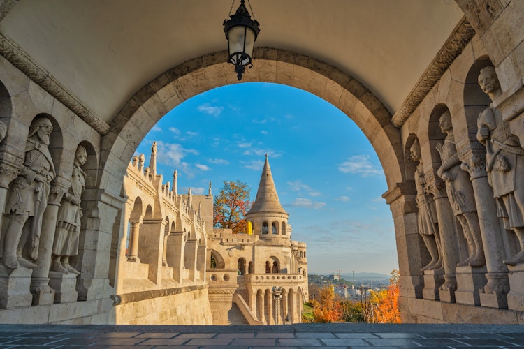 Den historiske Fiskerbastionen i Budapest med smukke efterårsfarver og udsigt over byens skyline gennem en stenbue, Ungarn