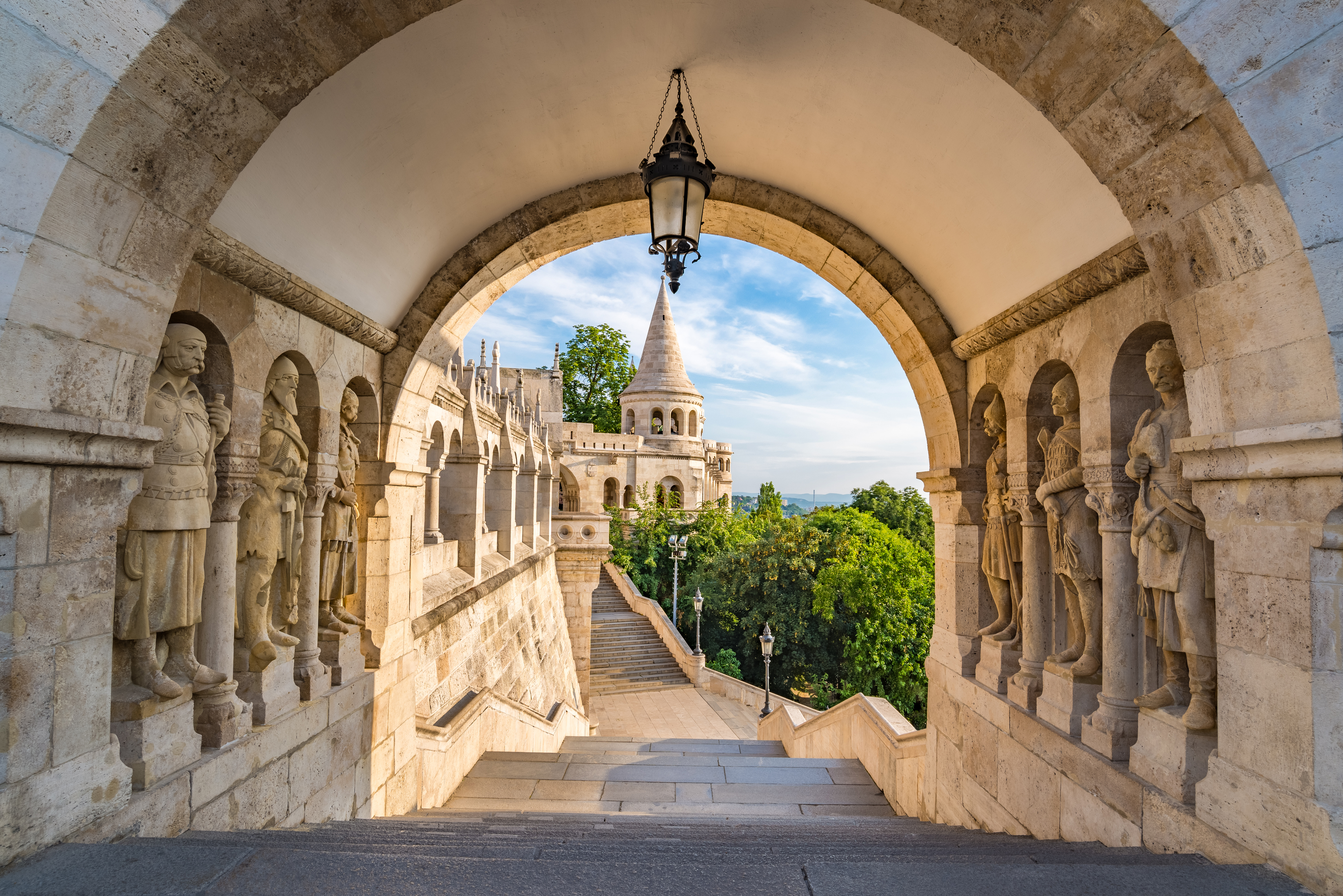 Historisk buegang ved Fiskerbastionen i Budapest med udsigt til den neo-romanske terrasse og tårne under blå himmel