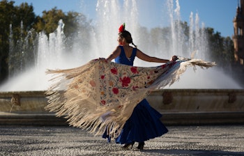 Smuk kvinde danser traditionel flamenco ved en fontæne i Andalusien, der viser ægte spansk kultur og folklore