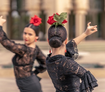 Traditionelle flamenco dansere i sorte blondekjoler med røde roser optræder i Sevilla, Andalusien