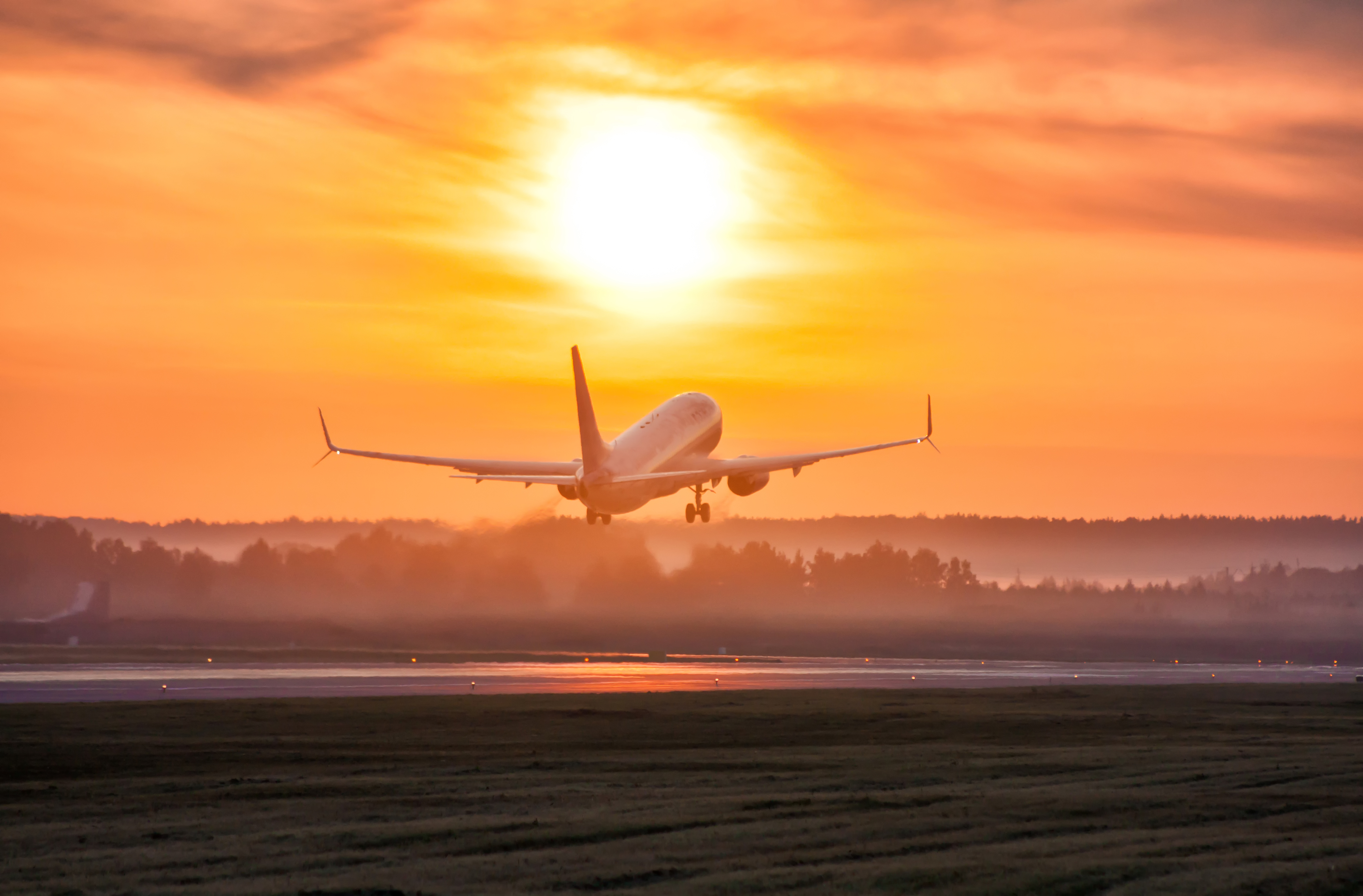 Passagerfly letter under gyldent solnedgangslys på lufthavn