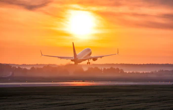 Passagerfly letter under gyldent solnedgangslys på lufthavn