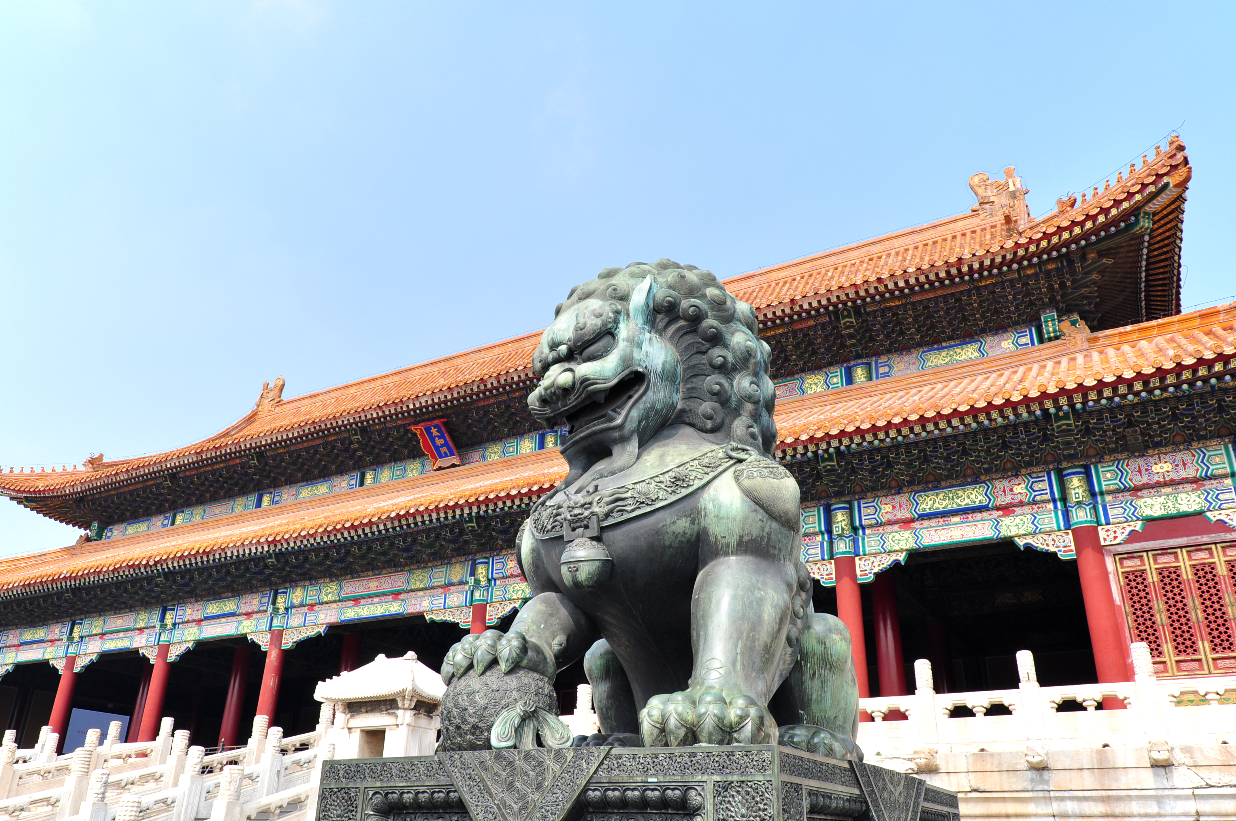 Bronzeløvestatue ved den Forbudte By i Beijing, Kina med traditionel kinesisk paladsarkitektur