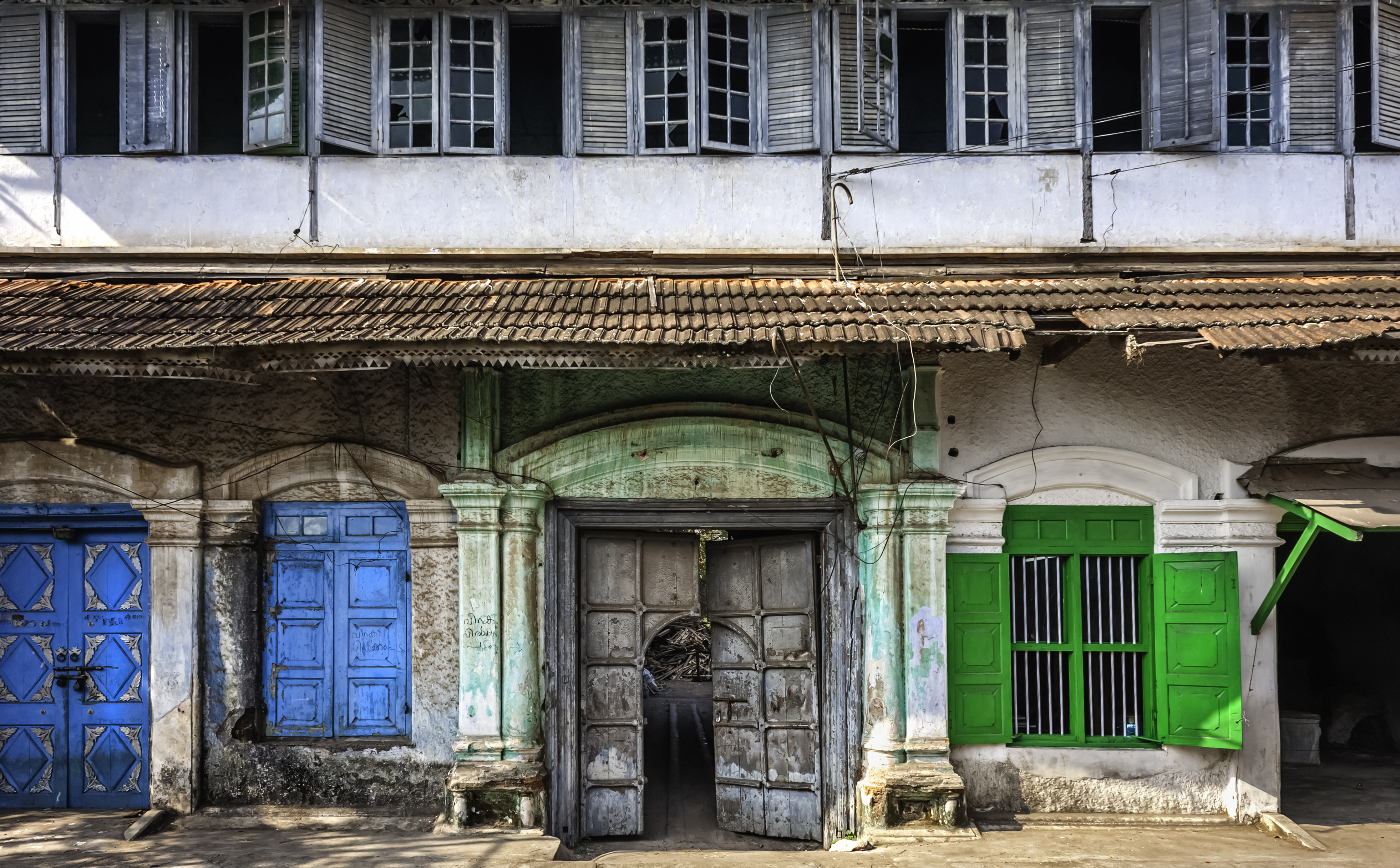 Historisk kolonibygning med farverige men slidte facader i Fort Kochi, Kerala, der både fungerer som bolig og krydderilager i den gamle bydel