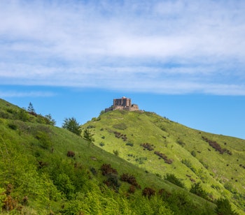 Historisk fæstning Forte Diamante på bakkekam i Genova med frodig grøn natur og blå himmel