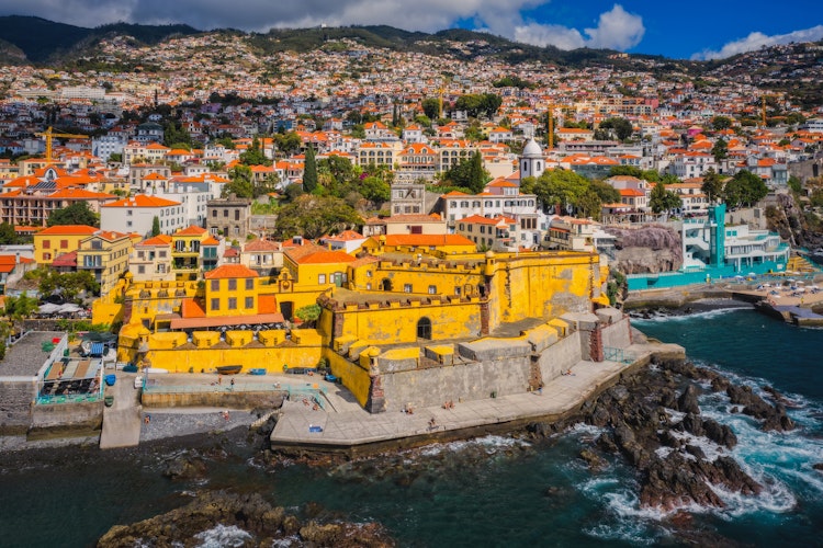 Luftfoto af den historiske gule fæstning Forte de São Tiago fra 1600-tallet ved kysten i Funchal på Madeira, hvor Restaurante do Forte serverer middag med udsigt over Atlanterhavet