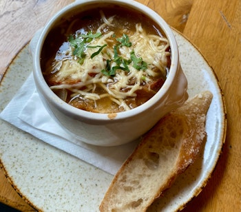 Traditionel fransk løgsuppe med smeltet ost og brød, serveret på en autentisk parisisk bistro