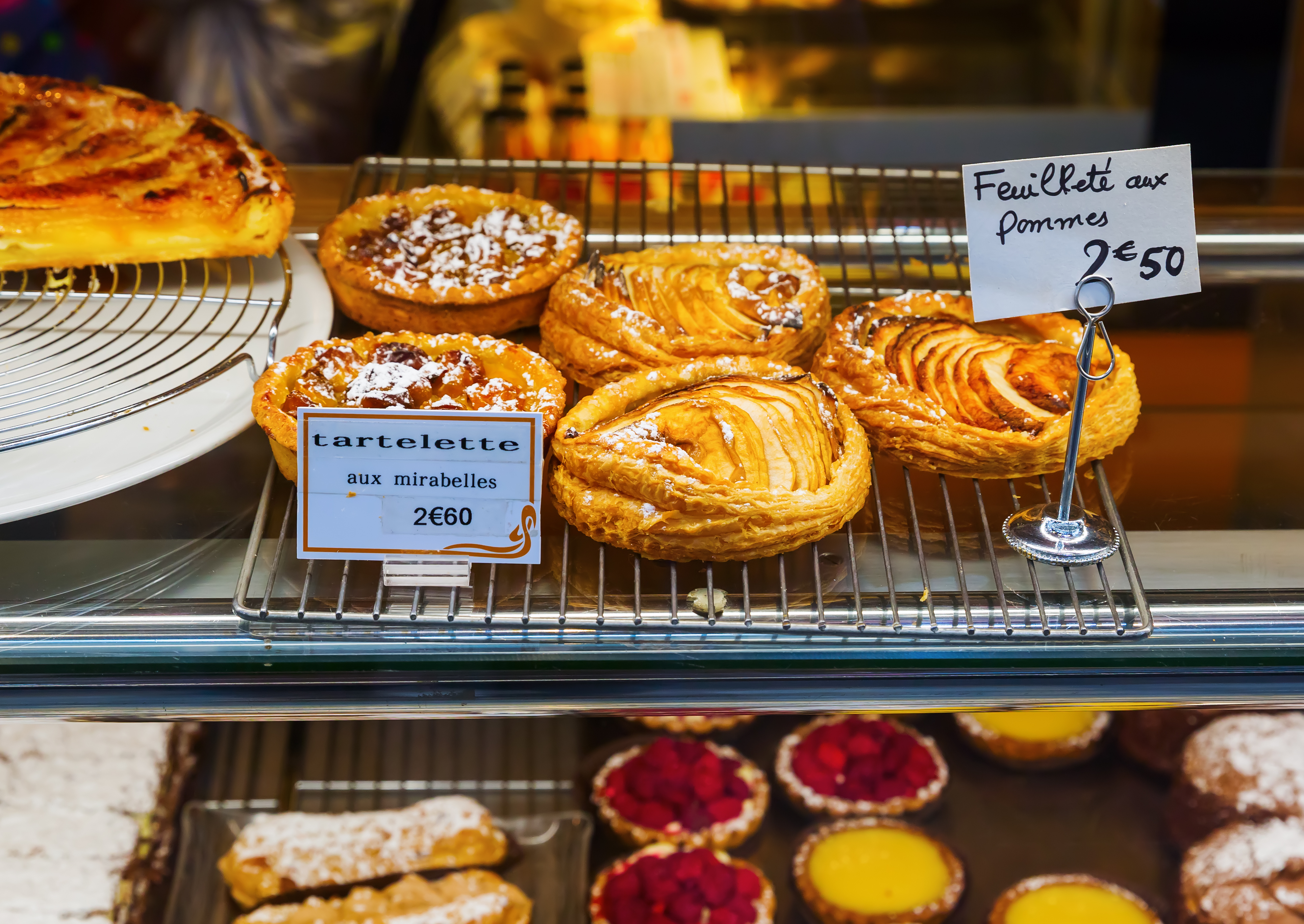 Franske konditorvarer udstillet i et bagervindue i Paris med æbletærter og mirabelle-tarteletter til 2,50-2,60 euro