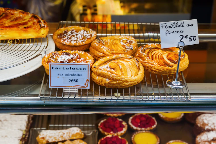Franske konditorvarer udstillet i et bagervindue i Paris med æbletærter og mirabelle-tarteletter til 2,50-2,60 euro