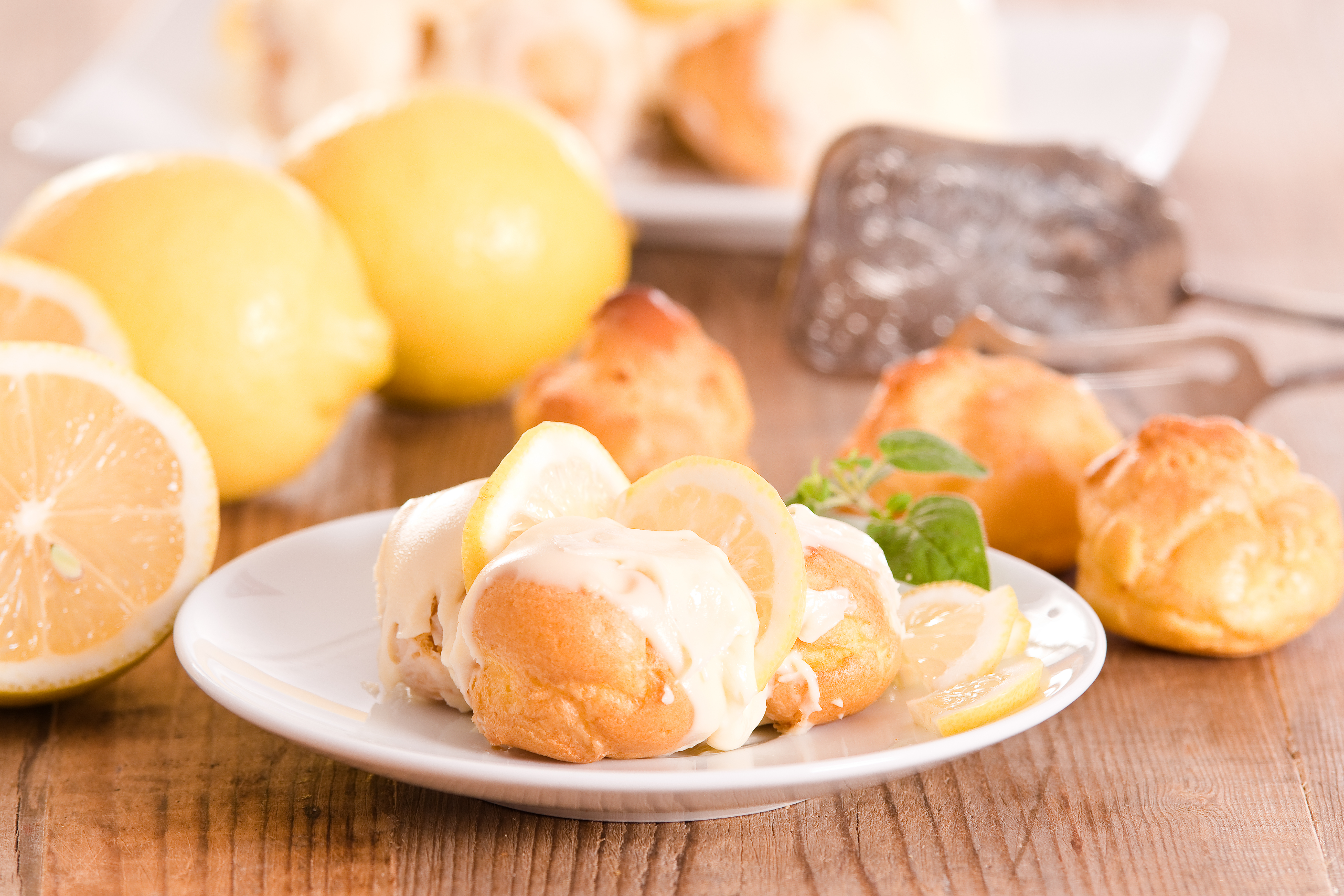 Franske citron-profiteroles med flødeskum og friske citronskiver serveret på hvid tallerken med myntepynt