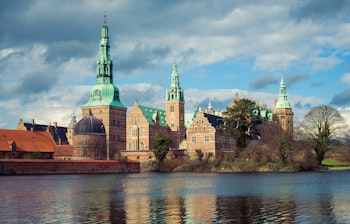 Frederiksborg Slot spejler sig i Slotssøen ved Hillerød på en smuk vinterdag