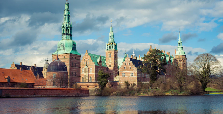 Frederiksborg Slot spejler sig i Slotssøen ved Hillerød på en smuk vinterdag