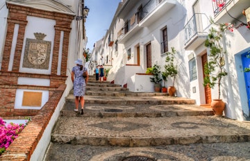 Malerisk hvid gade i Frigiliana, en traditionel pueblo blanco i Andalusien med smalle stier og farverige blomster