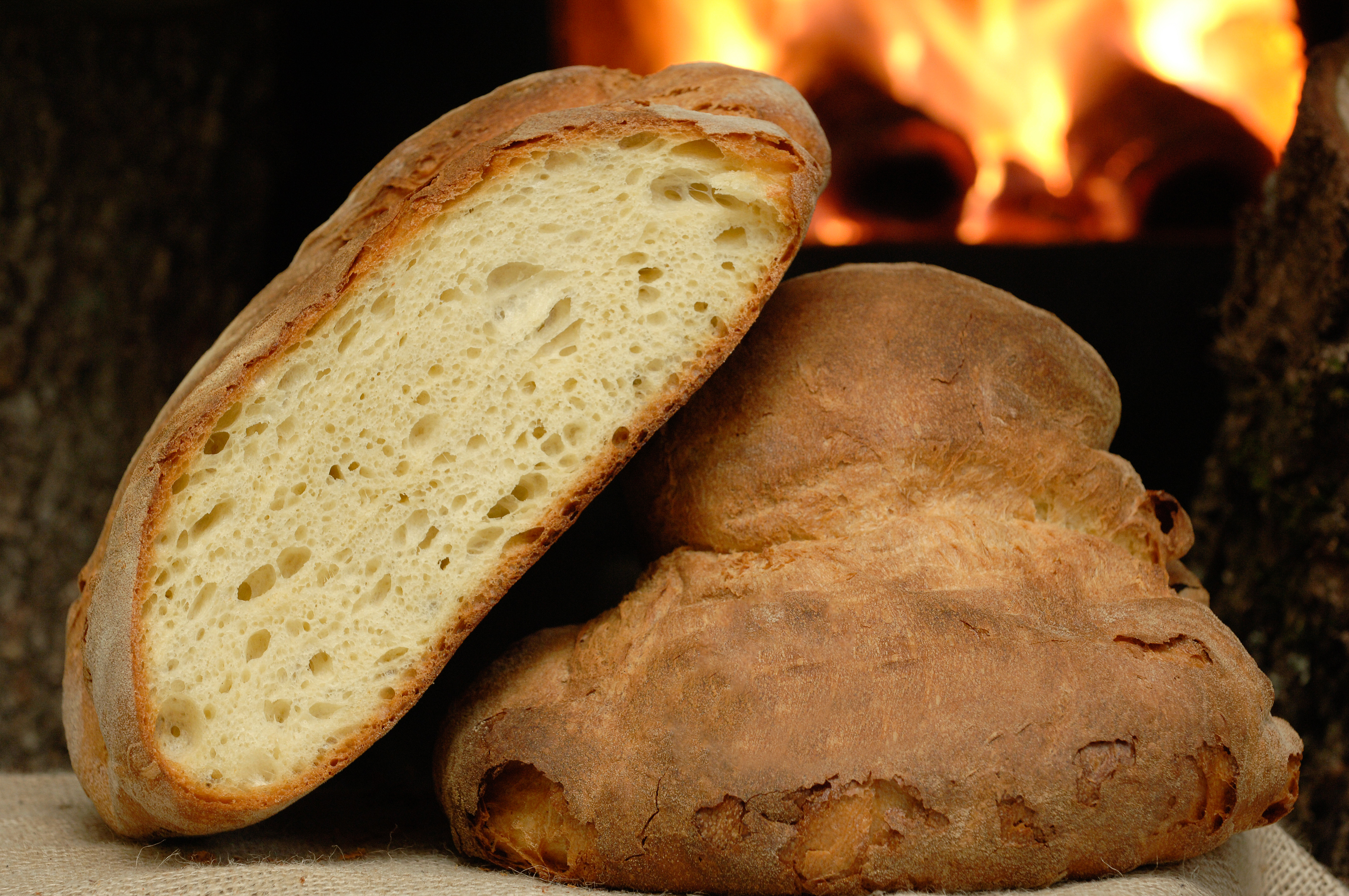 Friskbagt artisan brød skiver ved varm pejs viser europæisk bagertradition