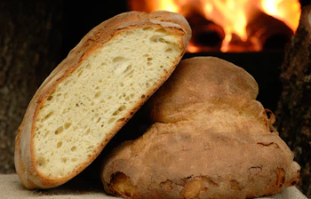 Friskbagt artisan brød skiver ved varm pejs viser europæisk bagertradition