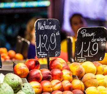 Farverige friske ferskner og nektariner med prisskilte på det berømte La Boqueria marked i Barcelona