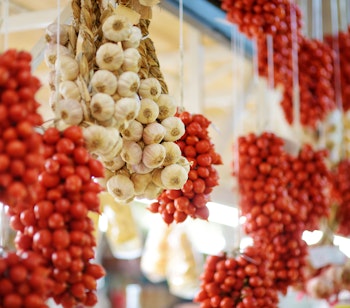 Farverige bundter af friske tomater og hvidløg hænger på det traditionelle Mercato Orientale marked i Genova, Italien