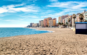 Smuk udsigt over Fuengirolas sandstrand med palmer, azurblåt Middelhav og kystbyggerier langs Costa del Sol i Malaga, Spanien