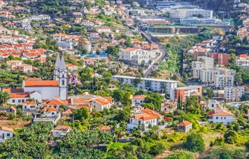 Smuk panoramaudsigt over Funchal by på Madeira med farverige bygninger mellem frodige grønne bakker og Atlanterhavets kystlinje
