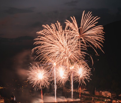 Spektakulært fyrværkeri over historisk stenbro med gyldne eksplosioner der oplyser europæisk bysilhuet om natten