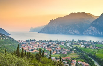 Betagende udsigt over Gardasøen ved solnedgang med en charmerende by omgivet af majestætiske bjerge i Norditalien