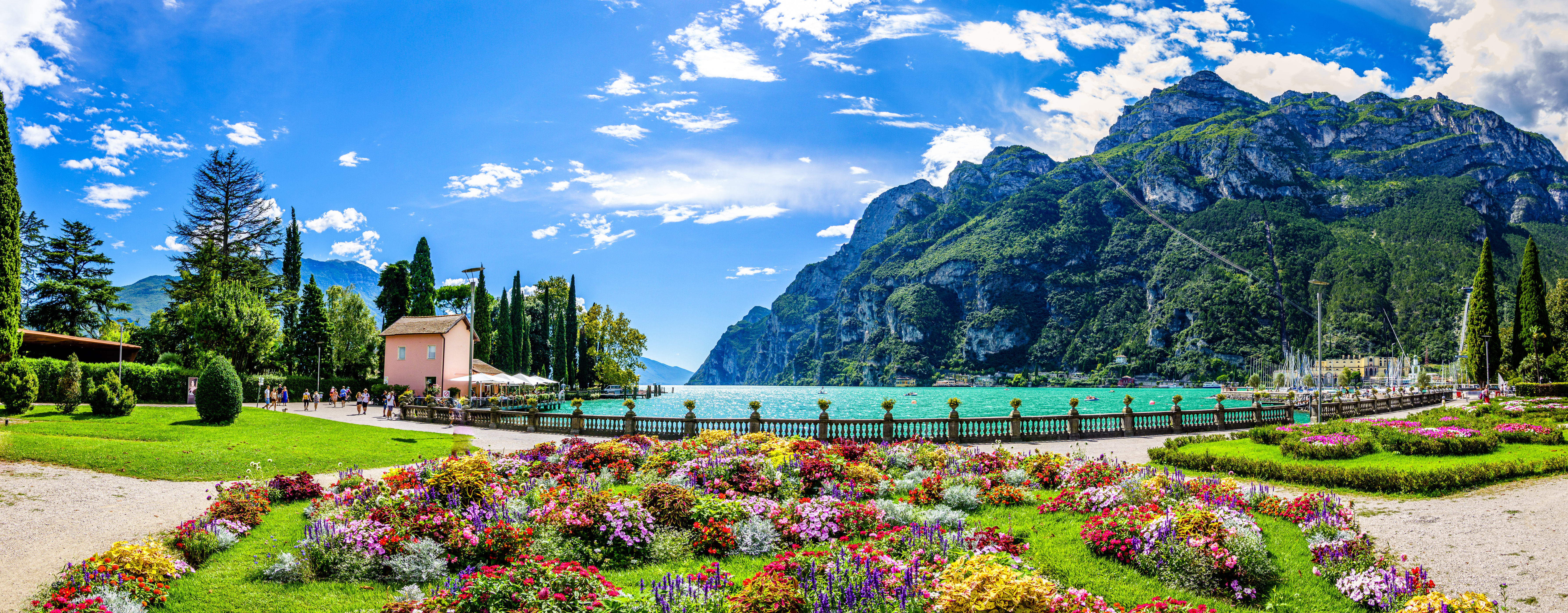 Fantastisk udsigt over Gardasøen med farverige blomsterhaver og bjerge i Riva del Garda, Italien