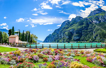 Fantastisk udsigt over Gardasøen med farverige blomsterhaver og bjerge i Riva del Garda, Italien