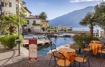 Idyllisk aftenudsigt over Gardasøens marina med sejlbåde, bjerge og italiensk middelhavsstemning