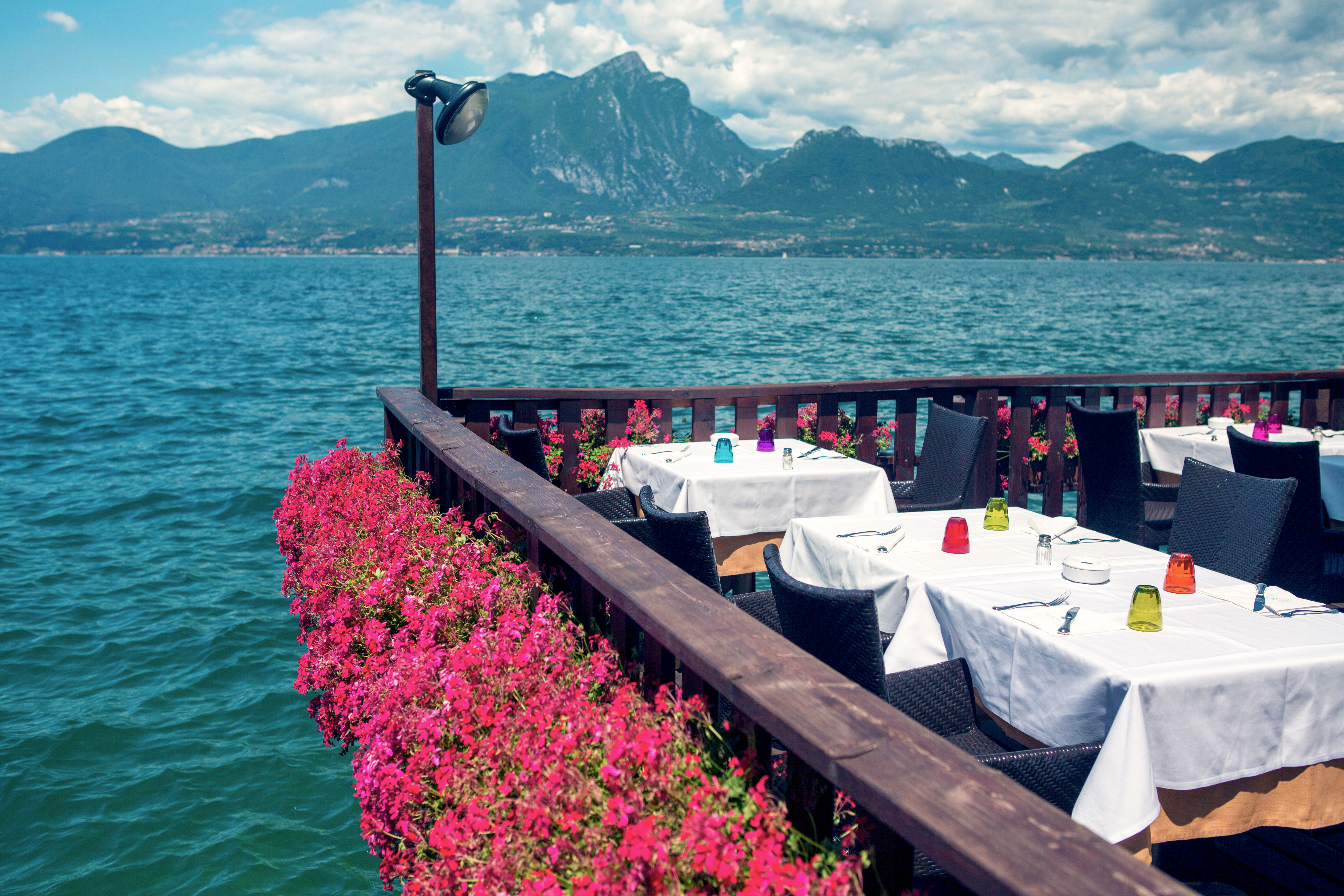 Romantisk restaurant med blomstersmykket terrasse direkte ved Gardasøens turkisblå vand med udsigt til bjergene