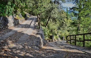 Historisk vandresti med serpentiner gennem frodig skov ved Monte Rocchetta nær Riva del Garda ved Gardasøen i Italien