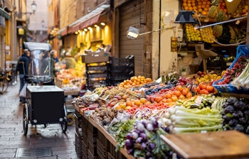Farverig madgade i Bologna med markedsboder fyldt med friske italienske frugter og grøntsager til gastronomiske oplevelser