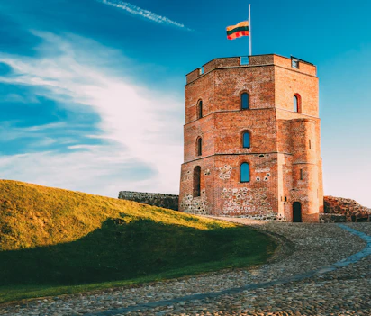 Gediminas-tårnet i Vilnius, Litauens historiske vartegn med det litauiske flag vajende fra toppen mod en blå himmel
