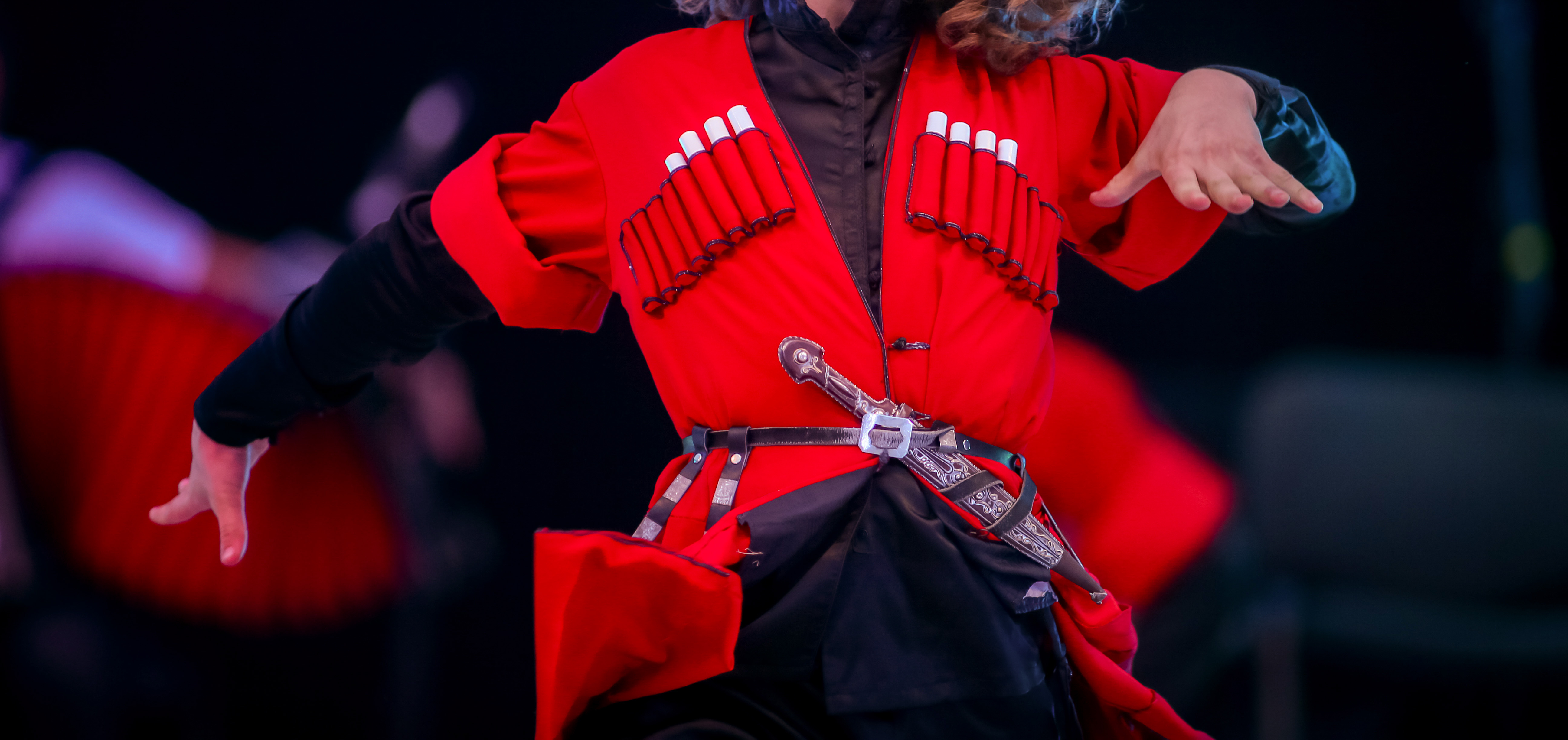 Traditionel georgisk folkedanser i rød nationaldragt under en kulturel forestilling, der viser Georgiens rige kulturarv