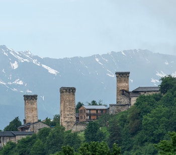 Historiske stenttårne i georgisk bjerglandsby med snedækkede Kaukasus-bjerge i baggrunden