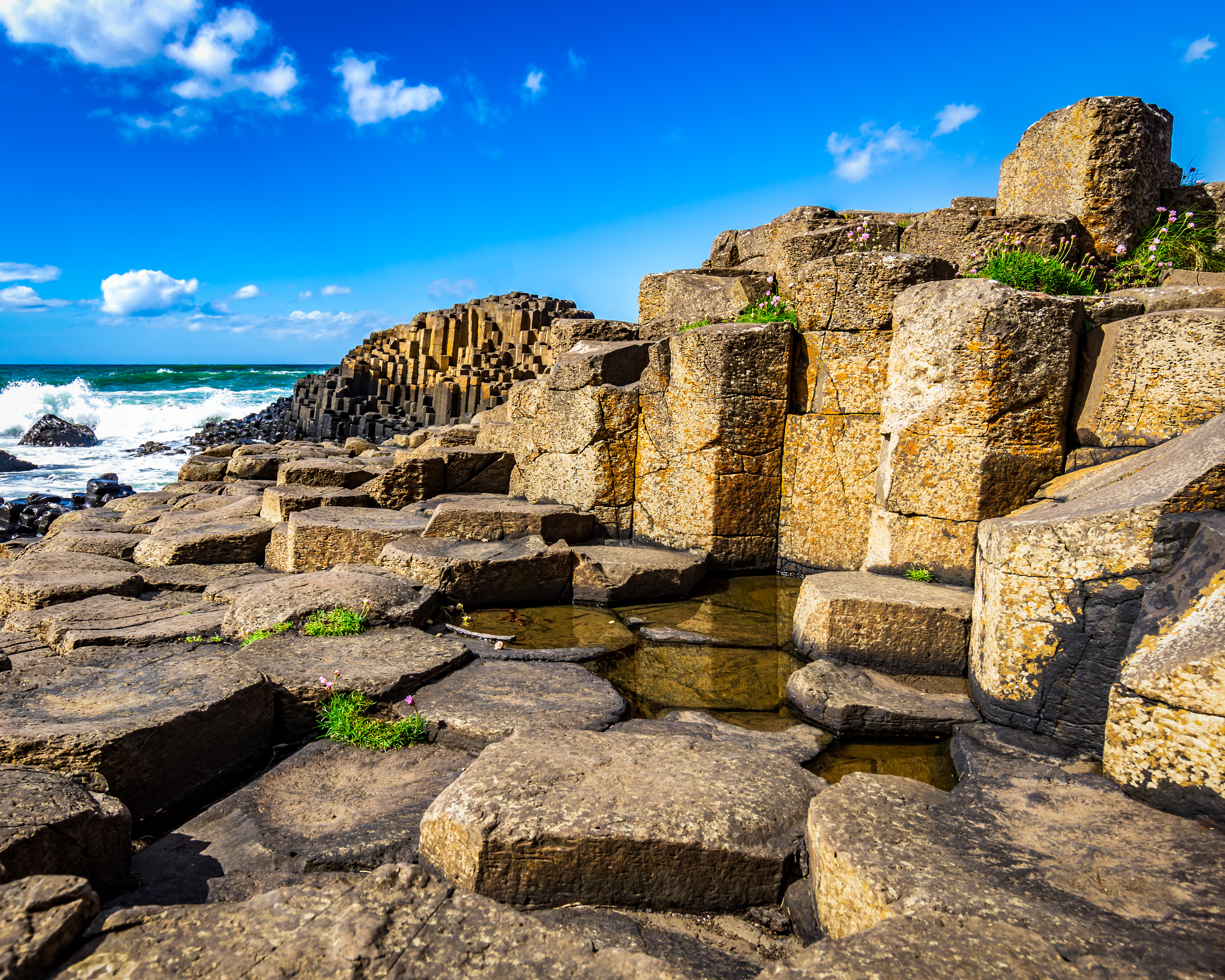 Antikke stenruiner ved Giant's Causeway i Nordirland med basaltsøjler og dramatisk kystlinje