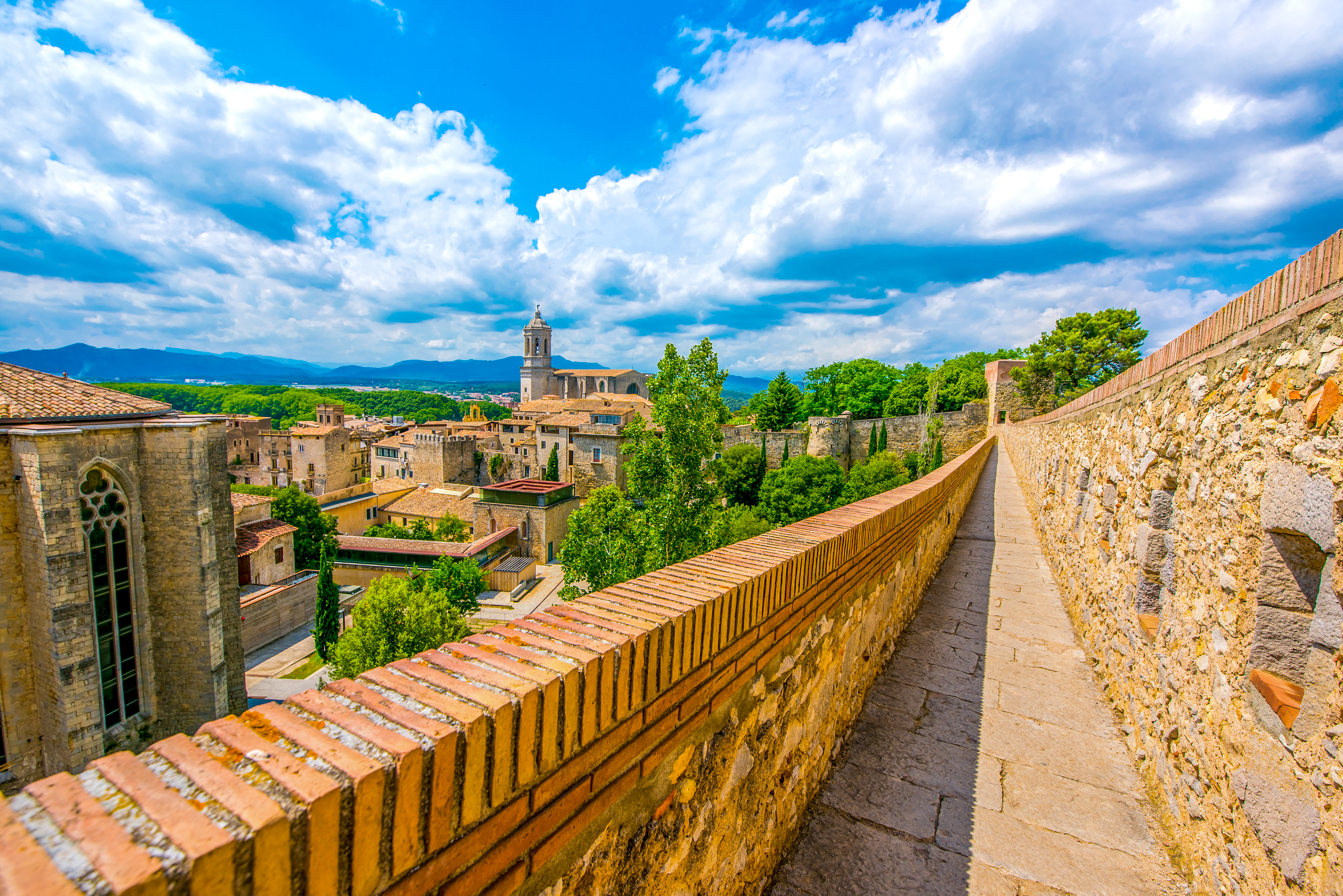 Panoramaudsigt over Girona med den imponerende katedral og farverige middelalderbygninger set fra bymuren i Catalonien
