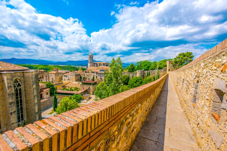 Panoramaudsigt over Girona med den imponerende katedral og farverige middelalderbygninger set fra bymuren i Catalonien