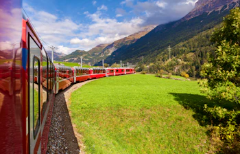Det berømte røde Glacier Express tog kører gennem de majestætiske schweiziske alper ved UNESCO verdensarvsområdet