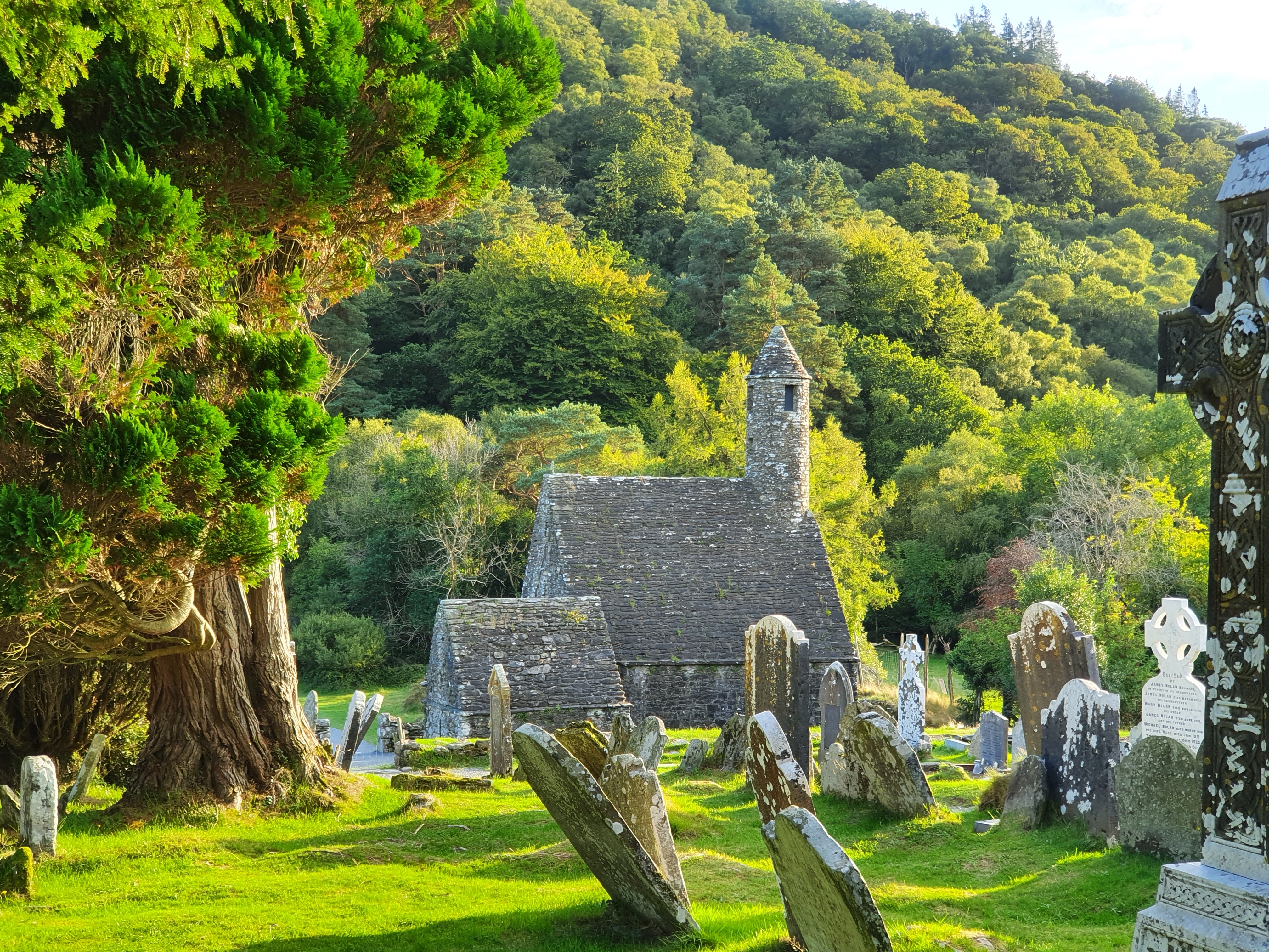 Gamle klosterruiner i Glendalough med rundtårn og keltiske gravsten i Wicklow-bjergene Irland