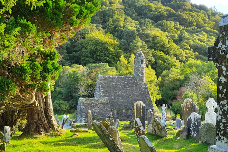 Gamle klosterruiner i Glendalough med rundtårn og keltiske gravsten i Wicklow-bjergene Irland