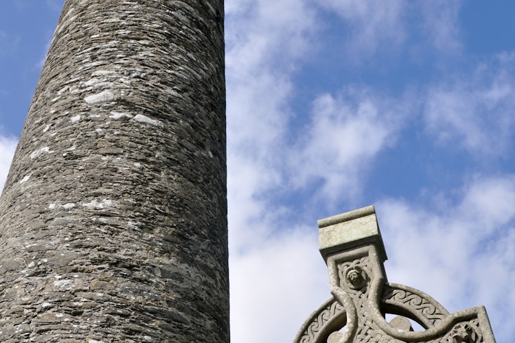Historisk rundtårn og keltisk kors i Glendalough klosterruiner, County Wicklow, Irland