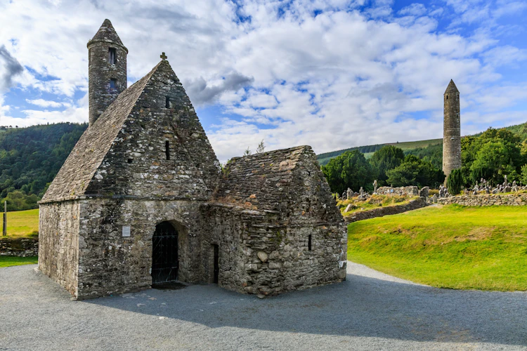 Saint Kevins Kirke og det runde tårn ved det middelalderlige klostersamfund Glendalough i County Wicklow, Irland